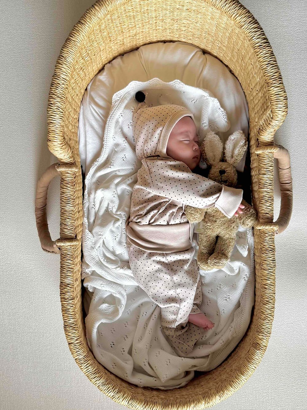 ドット柄のニューボーンセットと妖精のようなボンネットで眠る新生児