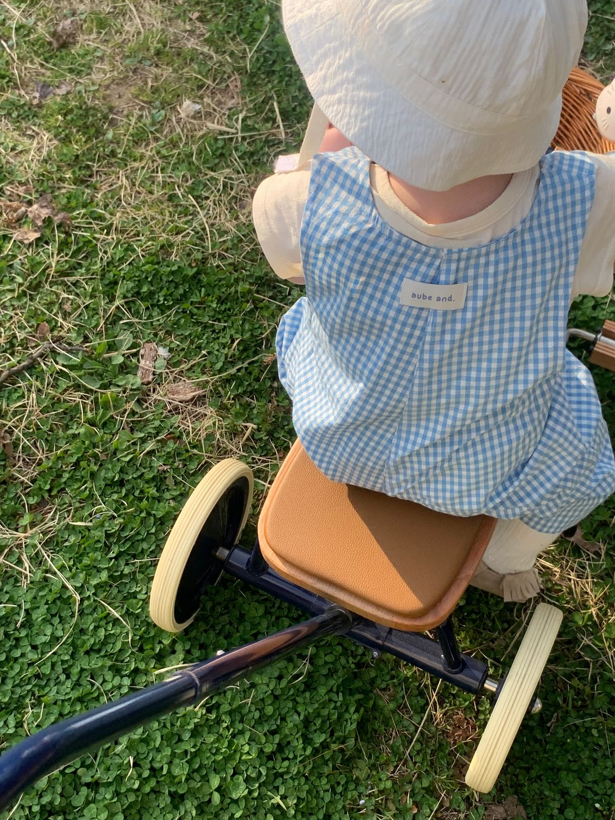 aube and.のブルーギンガムのオールインワンで三輪車に乗る子ども